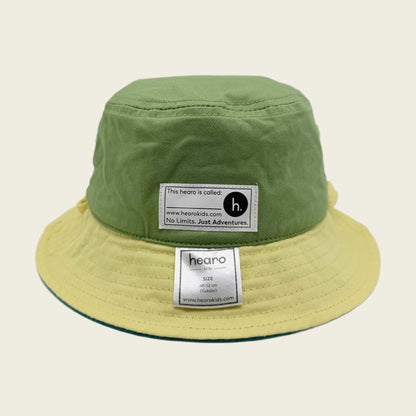 Green and yellow bucket hat with 'hearo' labels on a beige background
