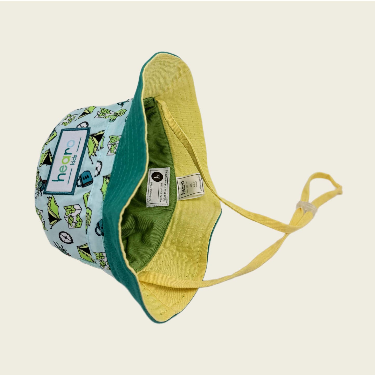 Bucket hat with green interior and patterned exterior on a beige background