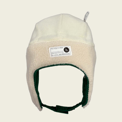 Beige fleece-lined winter hat with a name label on a beige background